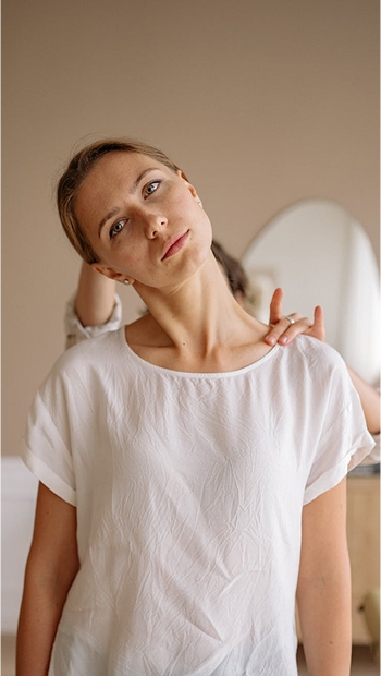 Mujer vestida de blanco moviendo su cuello de forma tranquila